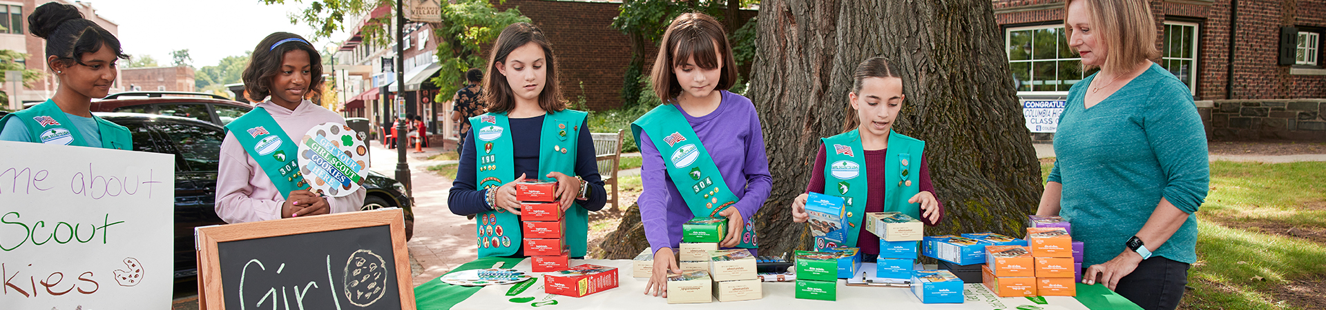 girl scouts and an adult at a cookie booth 