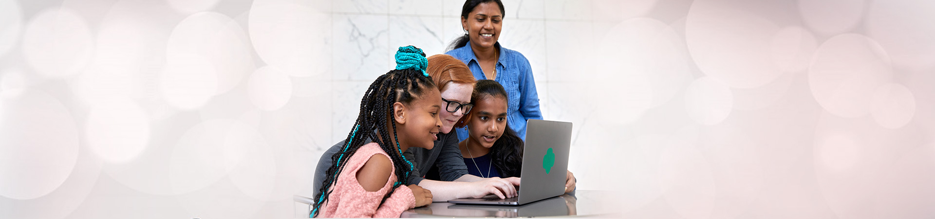  girls and an adult gathered around a computer 
