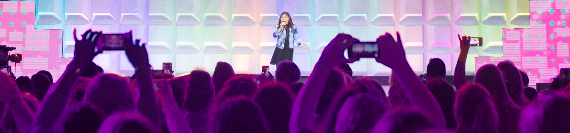  girl on stage singing to a crowd 