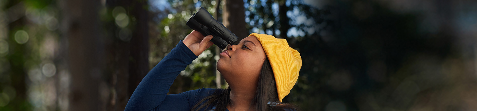  high school girl holding binoculars outside in woods 
