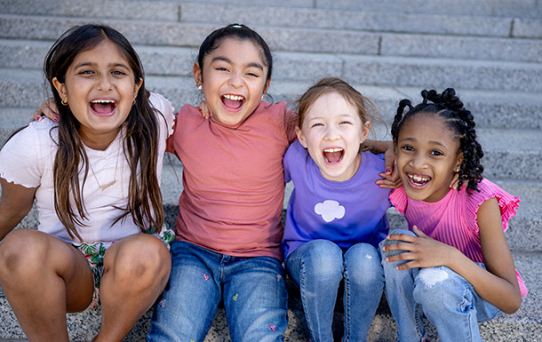 Six Girl Scouts of various ages sitting on a couch together